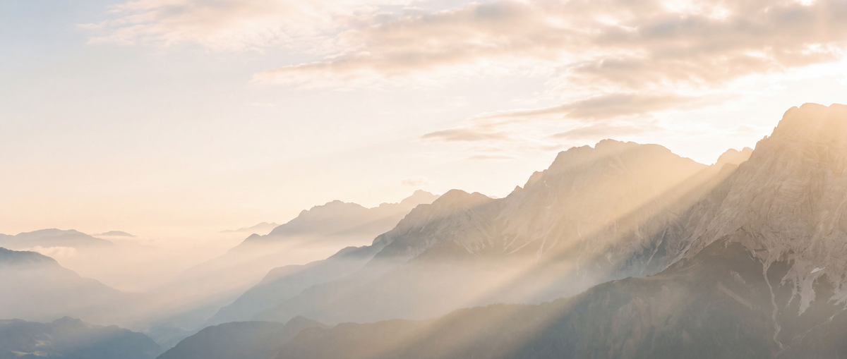 Golden sunrise light breaking through the clouds over misty mountains